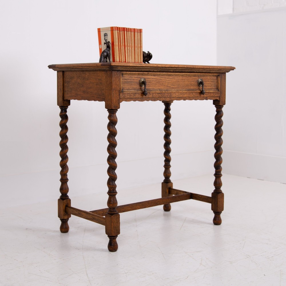 An antique English oak side table featuring a single drawer with metal drop handles, set upon four barley twist legs connected by an H-stretcher base. View XI
