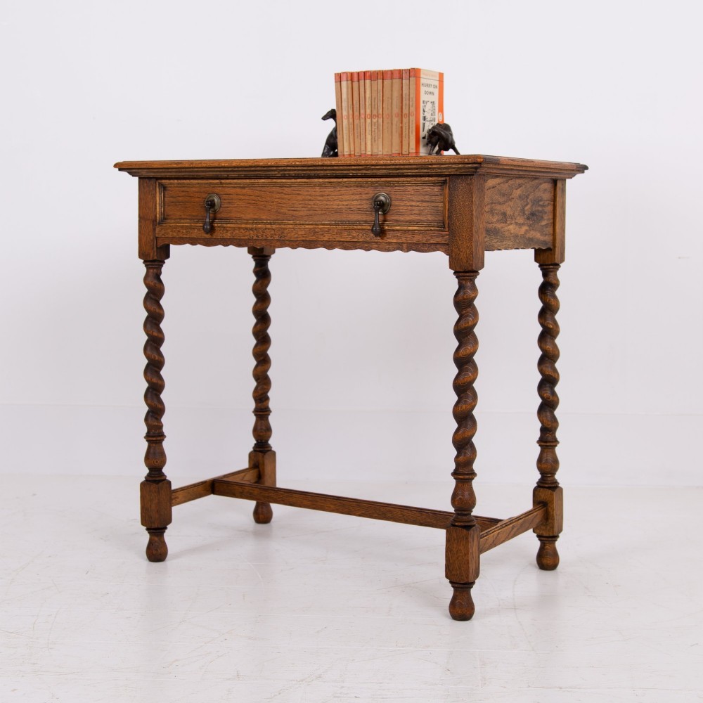An antique English oak side table featuring a single drawer with metal drop handles, set upon four barley twist legs connected by an H-stretcher base. View XIII