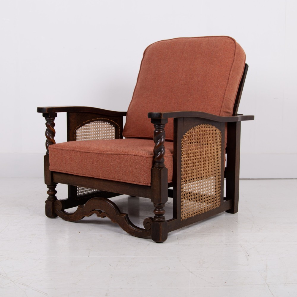 A pair of dark oak Edwardian armchairs featuring barley twist front supports, woven cane side panels, and thick terracotta fabric cushions. View II
