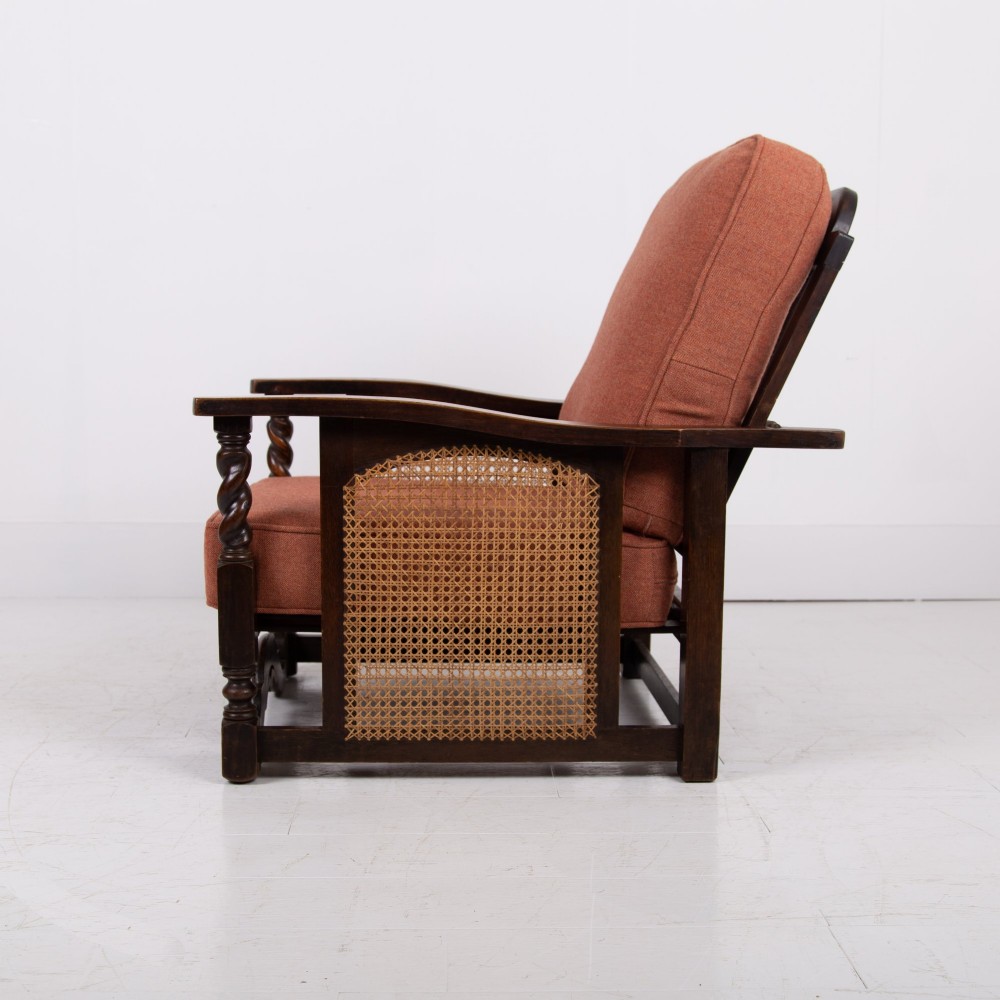 A pair of dark oak Edwardian armchairs featuring barley twist front supports, woven cane side panels, and thick terracotta fabric cushions. View III