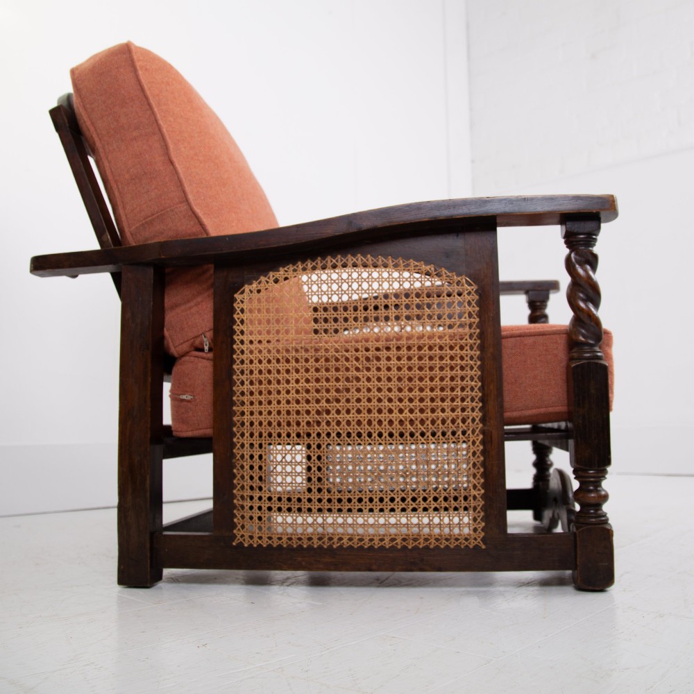 A pair of dark oak Edwardian armchairs featuring barley twist front supports, woven cane side panels, and thick terracotta fabric cushions. View V
