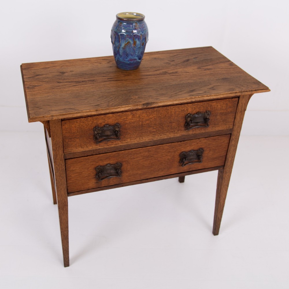 An early 20th-century oak side table with two drawers, decorative metal drop handles, and tapered square legs. View II