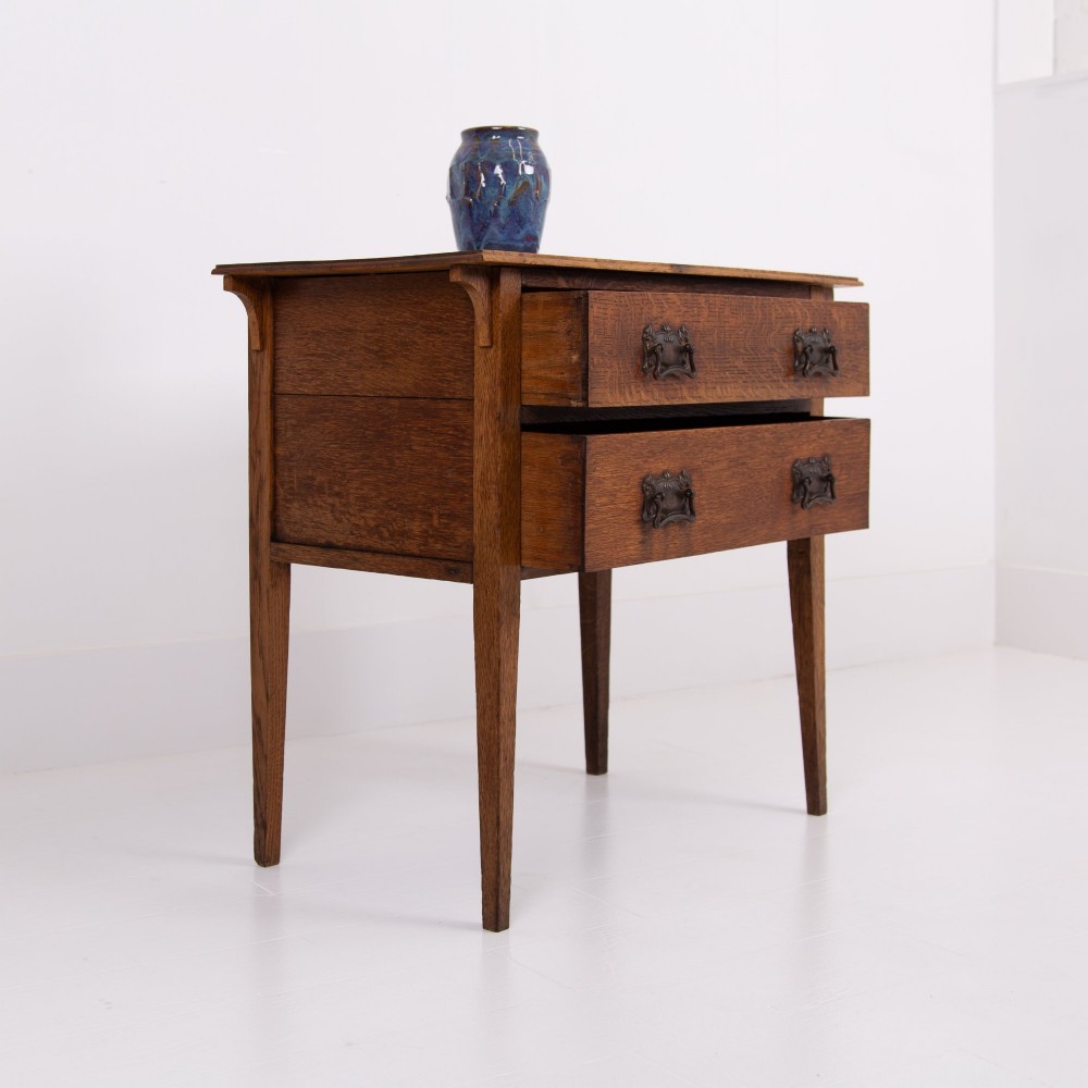 An early 20th-century oak side table with two drawers, decorative metal drop handles, and tapered square legs. View III
