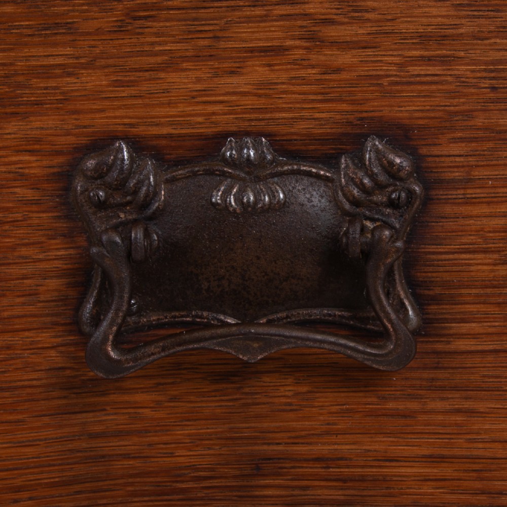 An early 20th-century oak side table with two drawers, decorative metal drop handles, and tapered square legs. View IV
