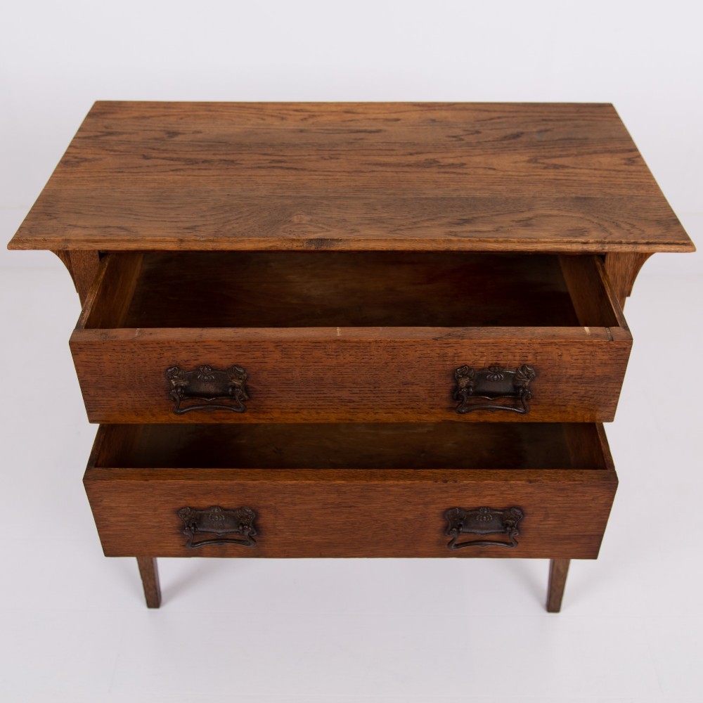 An early 20th-century oak side table with two drawers, decorative metal drop handles, and tapered square legs. View V