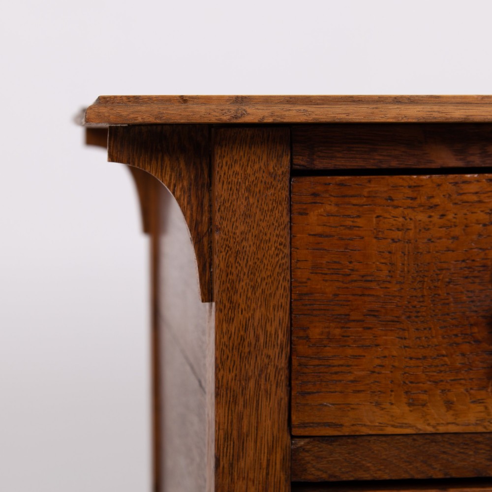 An early 20th-century oak side table with two drawers, decorative metal drop handles, and tapered square legs. View VII