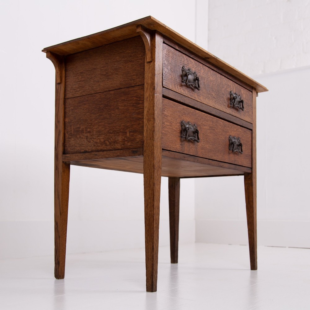An early 20th-century oak side table with two drawers, decorative metal drop handles, and tapered square legs. View VIII