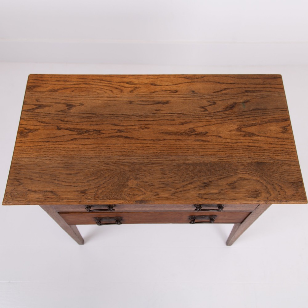 An early 20th-century oak side table with two drawers, decorative metal drop handles, and tapered square legs. View IX