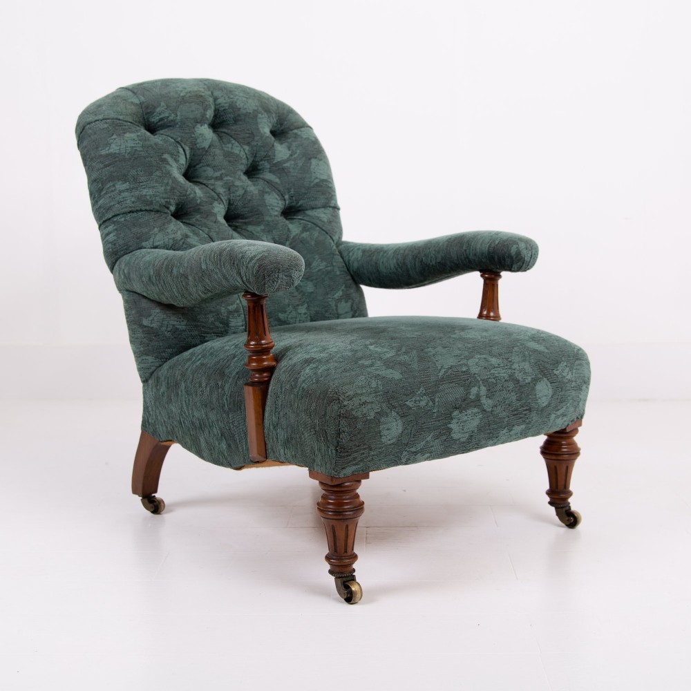 A profile view of a Victorian walnut open library armchair with dark green button-backed upholstery, turned front legs, and brass castors. View IX