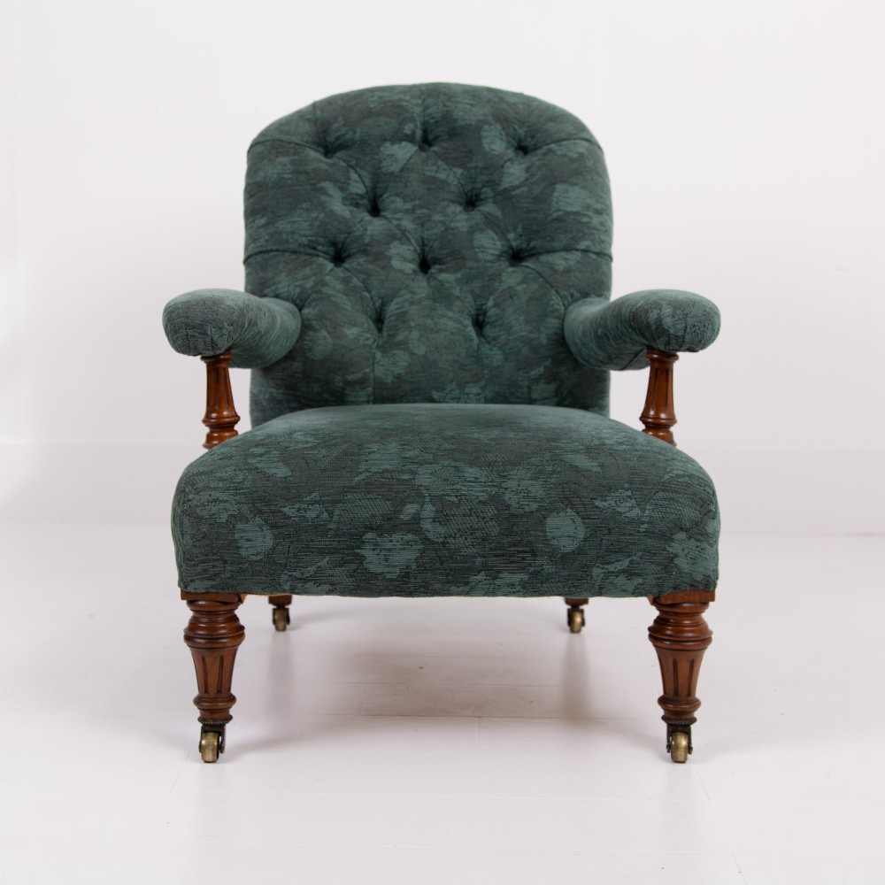 A profile view of a Victorian walnut open library armchair with dark green button-backed upholstery, turned front legs, and brass castors. View XII