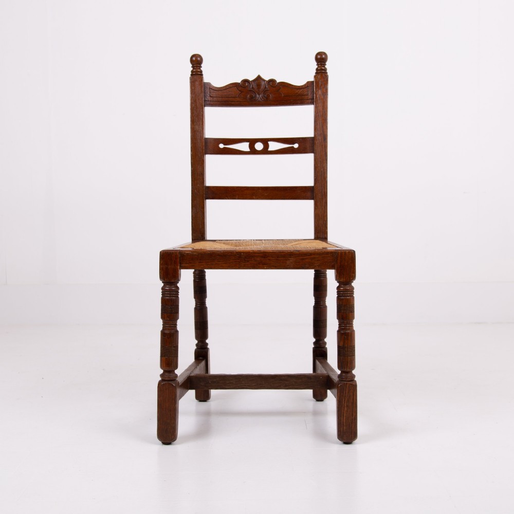 A set of six dark oak country dining chairs featuring hand-woven rush seats, carved top rails, and turned front legs. View IV