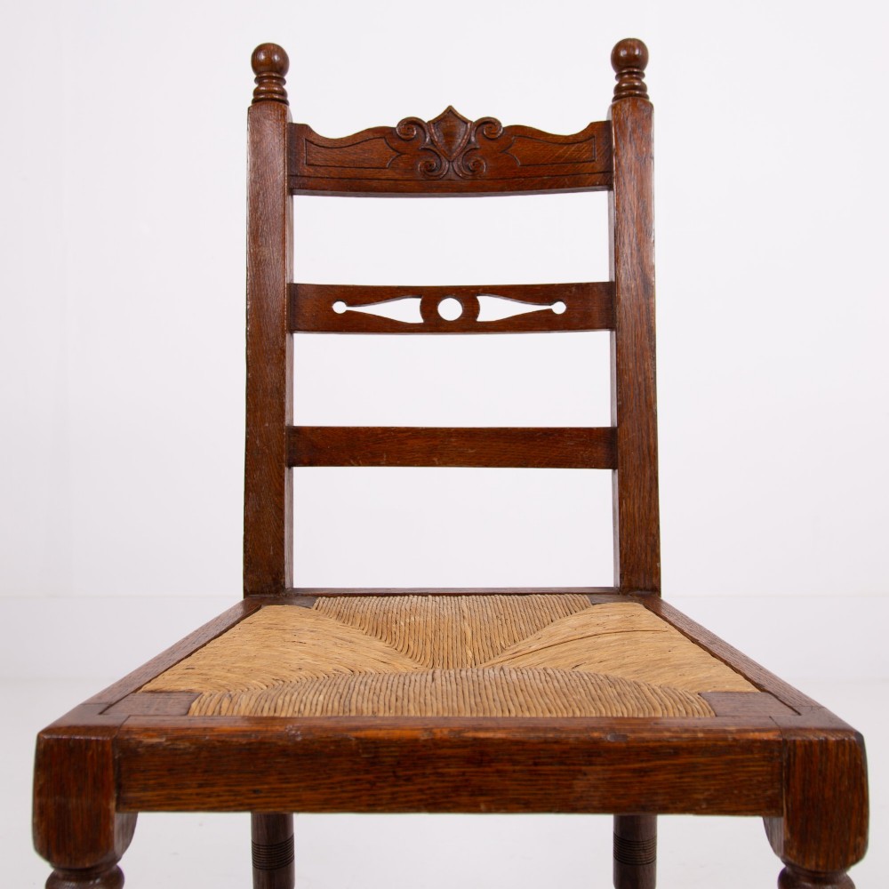 A set of six dark oak country dining chairs featuring hand-woven rush seats, carved top rails, and turned front legs. View V