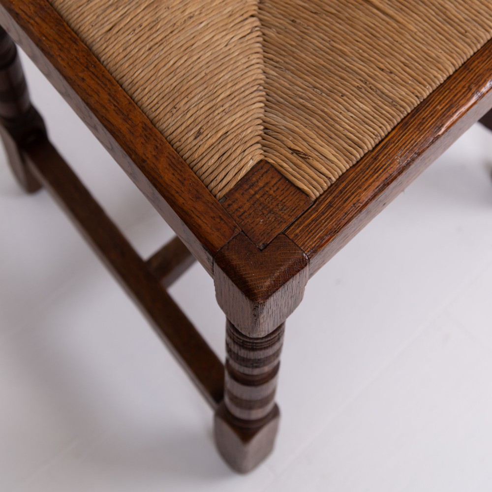 A set of six dark oak country dining chairs featuring hand-woven rush seats, carved top rails, and turned front legs. View IX
