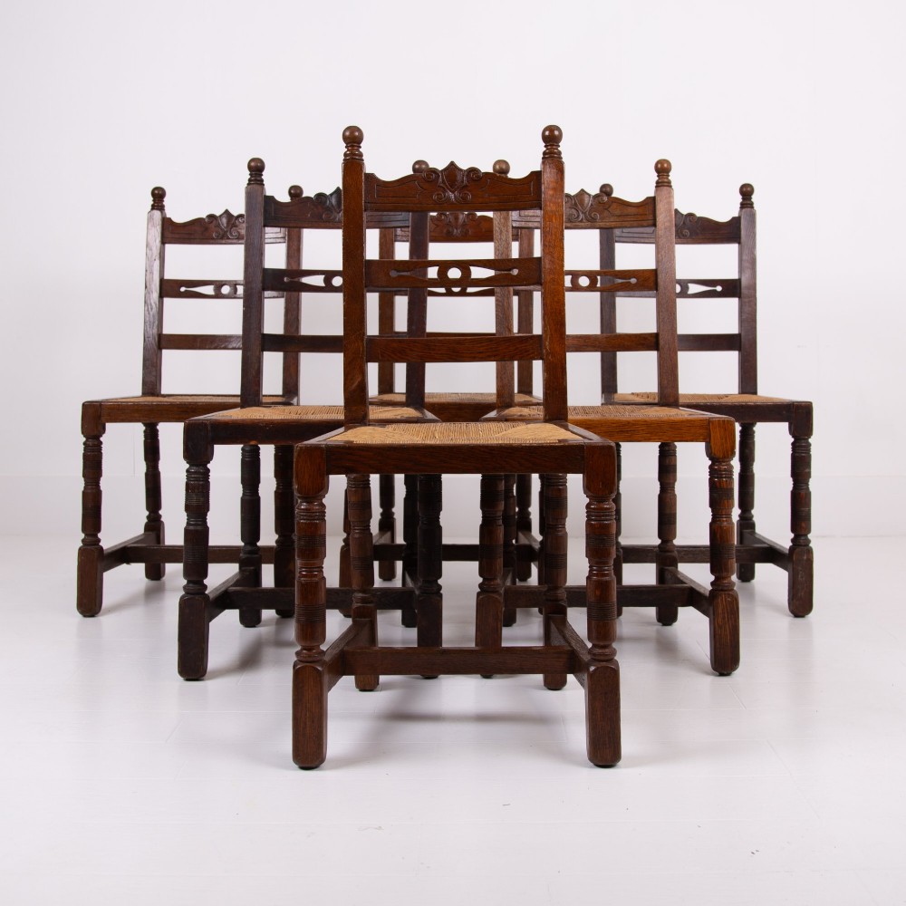 A set of six dark oak country dining chairs featuring hand-woven rush seats, carved top rails, and turned front legs. View XIII