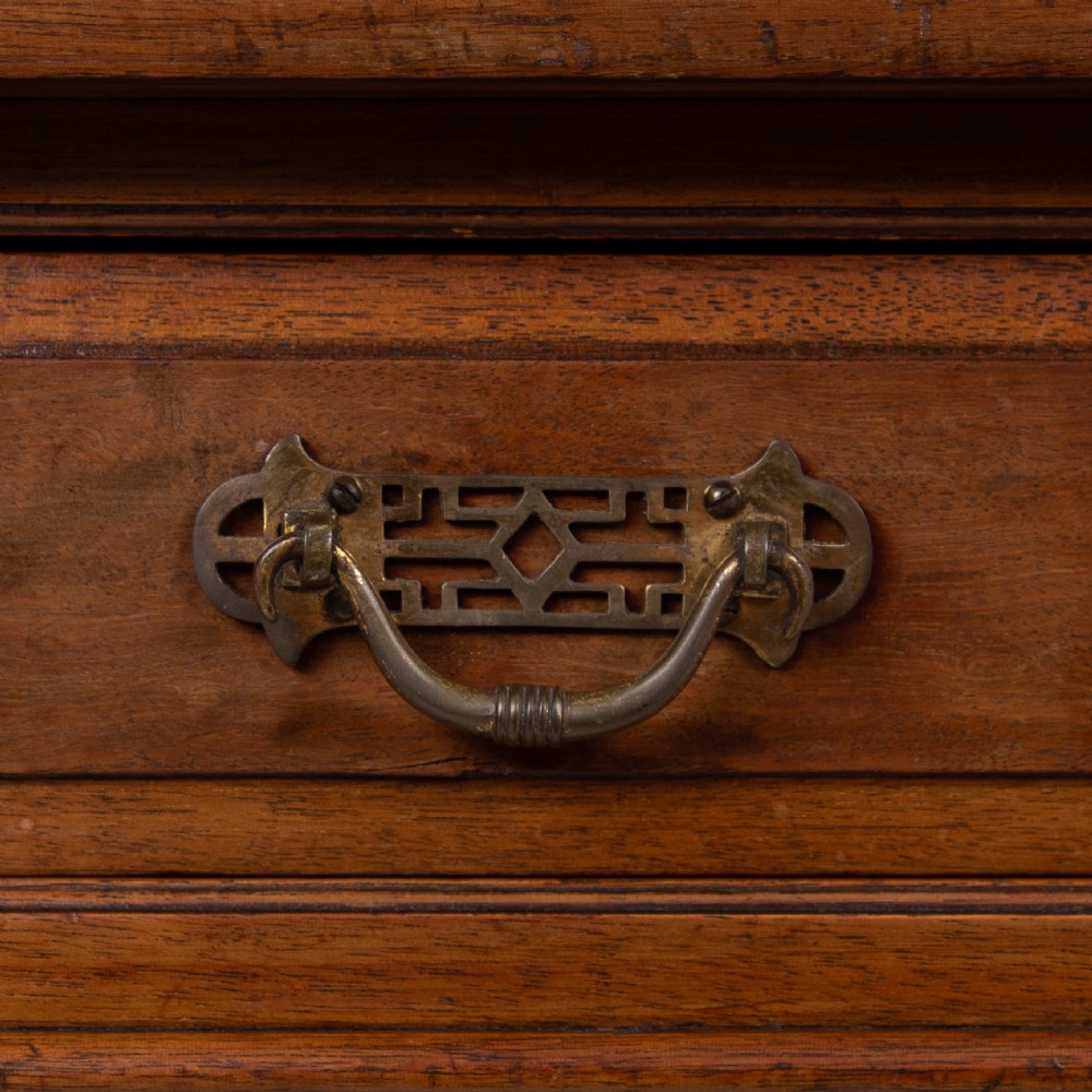 A late 19th-century walnut writing desk featuring two drawers with brass handles, turned legs on castors, and an inset leather top. View IV