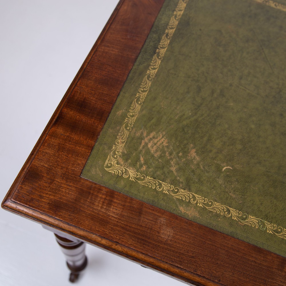 A late 19th-century walnut writing desk featuring two drawers with brass handles, turned legs on castors, and an inset leather top. View VIII