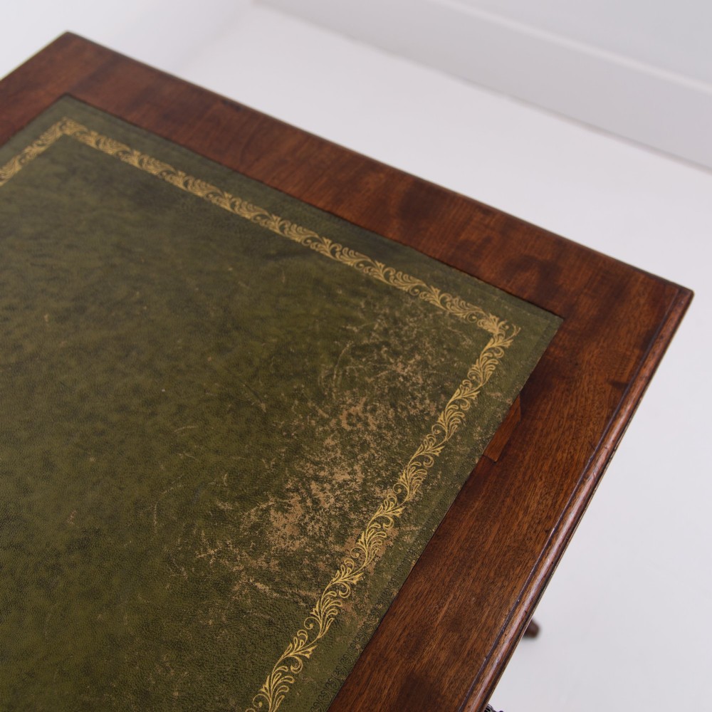 A late 19th-century walnut writing desk featuring two drawers with brass handles, turned legs on castors, and an inset leather top. View IX
