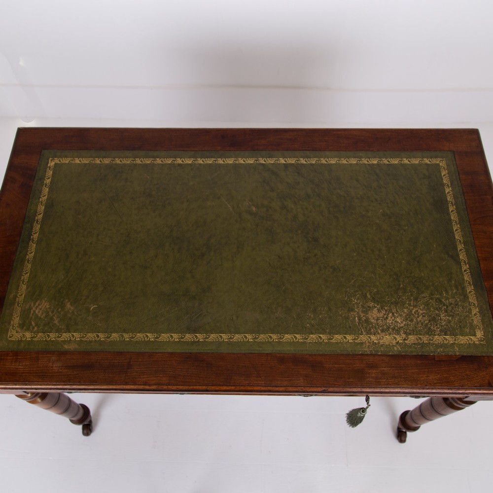 A late 19th-century walnut writing desk featuring two drawers with brass handles, turned legs on castors, and an inset leather top. View X