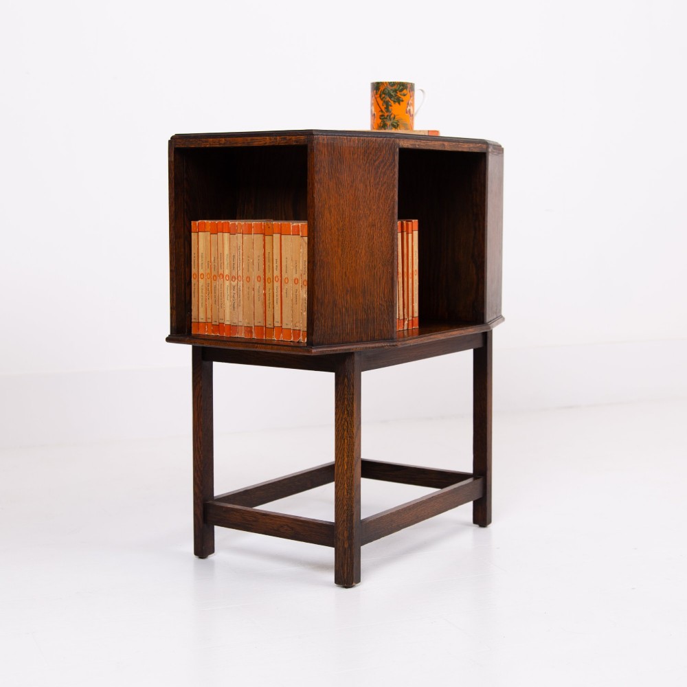An Art Deco dark oak side table featuring an octagonal top, open central niche, side book compartments, and straight legs with square stretchers. View III
