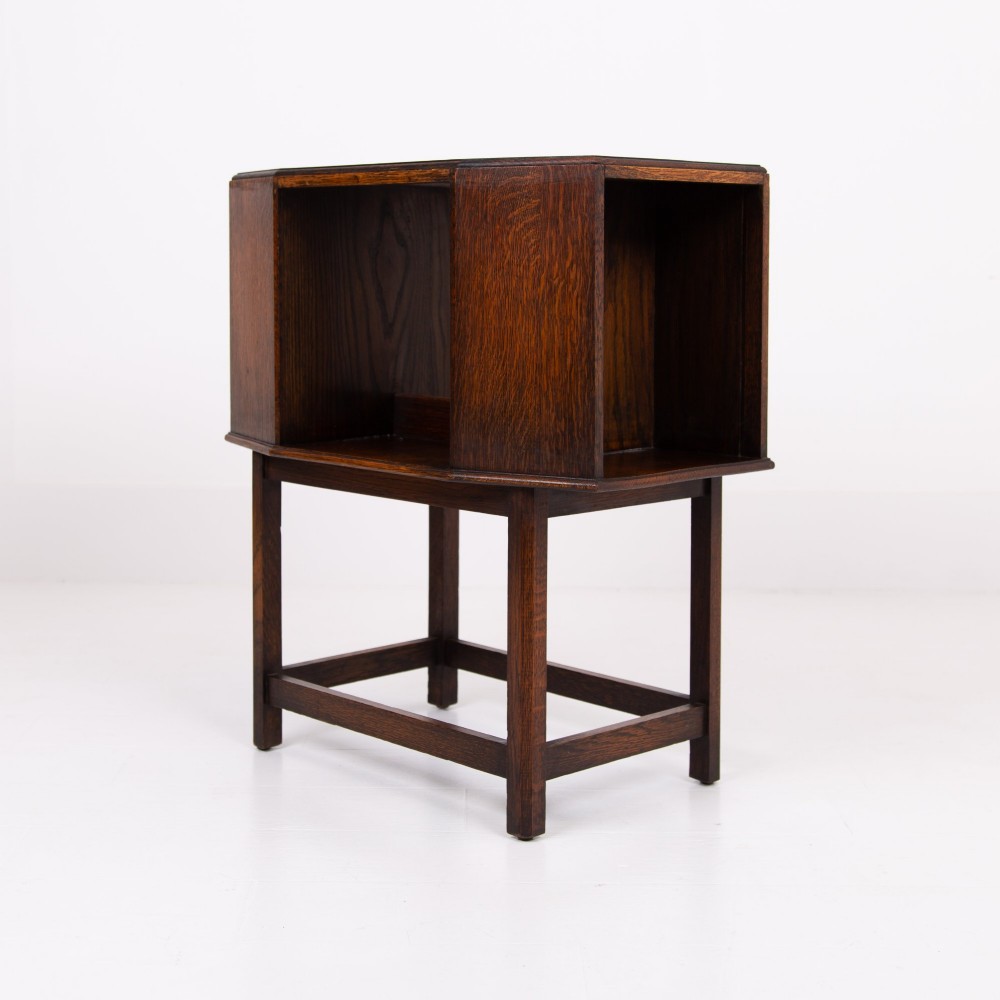 An Art Deco dark oak side table featuring an octagonal top, open central niche, side book compartments, and straight legs with square stretchers. View IV