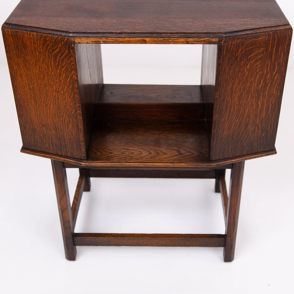 An Art Deco dark oak side table featuring an octagonal top, open central niche, side book compartments, and straight legs with square stretchers. View VII