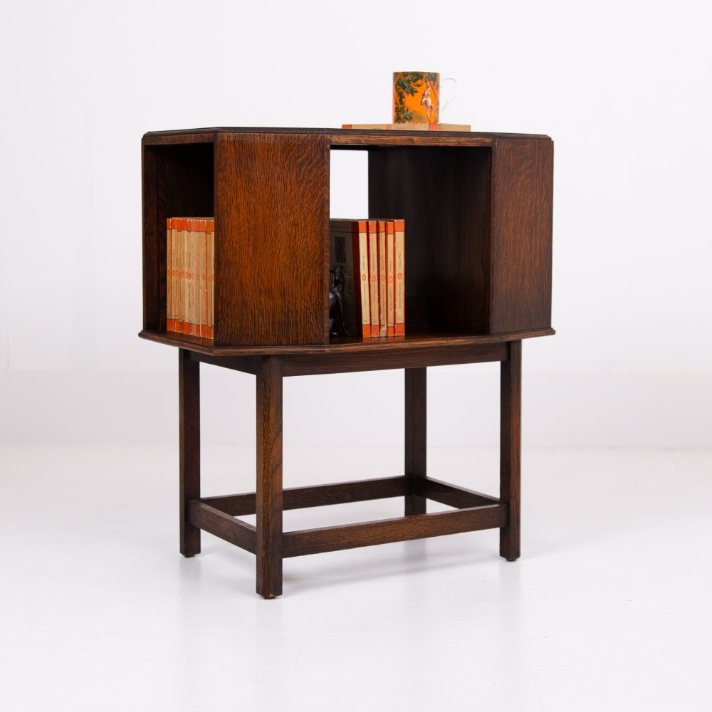 An Art Deco dark oak side table featuring an octagonal top, open central niche, side book compartments, and straight legs with square stretchers. View XII