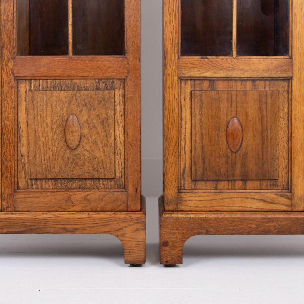 A matching pair of 1930s solid English oak bookcases featuring glazed twin doors above oval-carved lower door panels. View IV