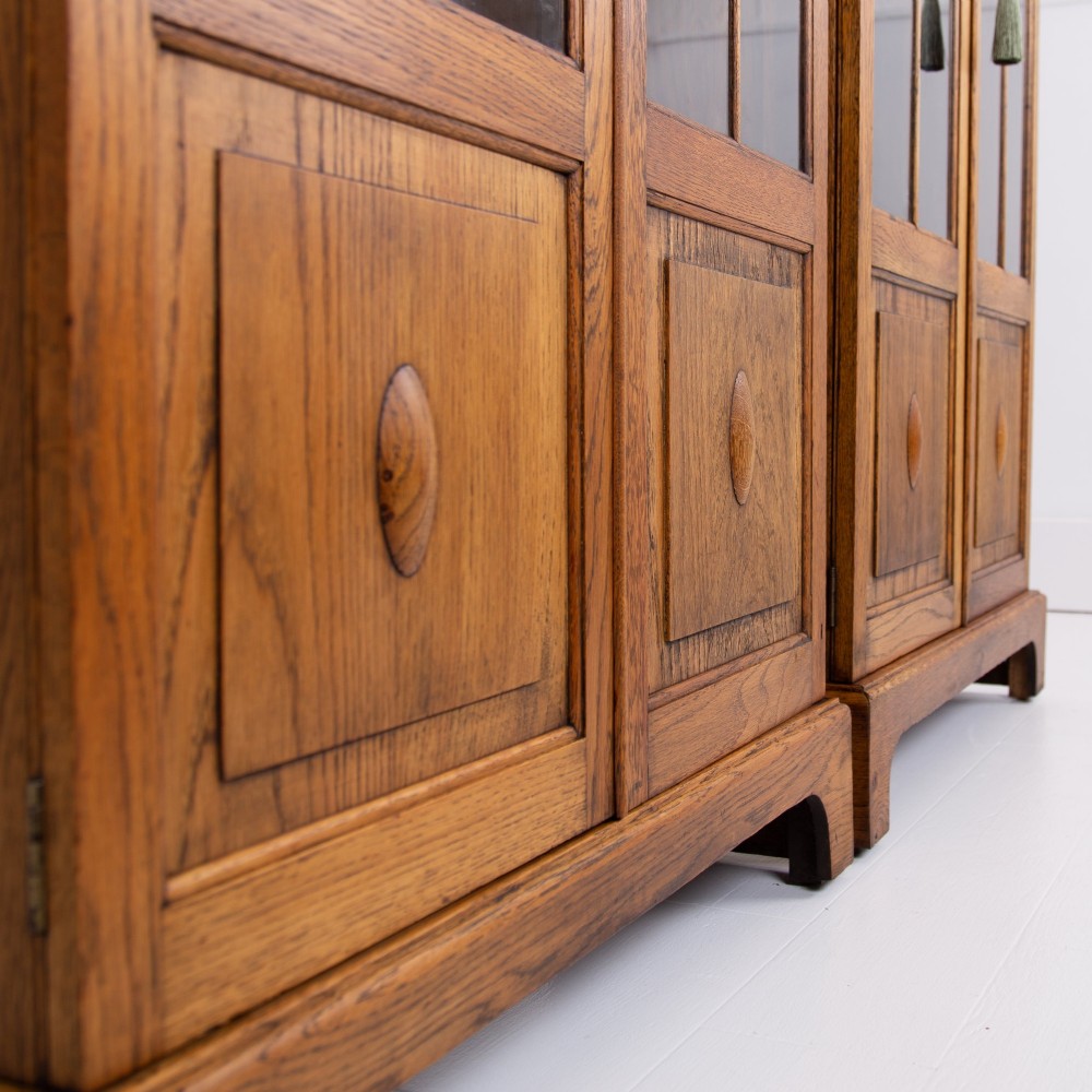 A matching pair of 1930s solid English oak bookcases featuring glazed twin doors above oval-carved lower door panels. View VI