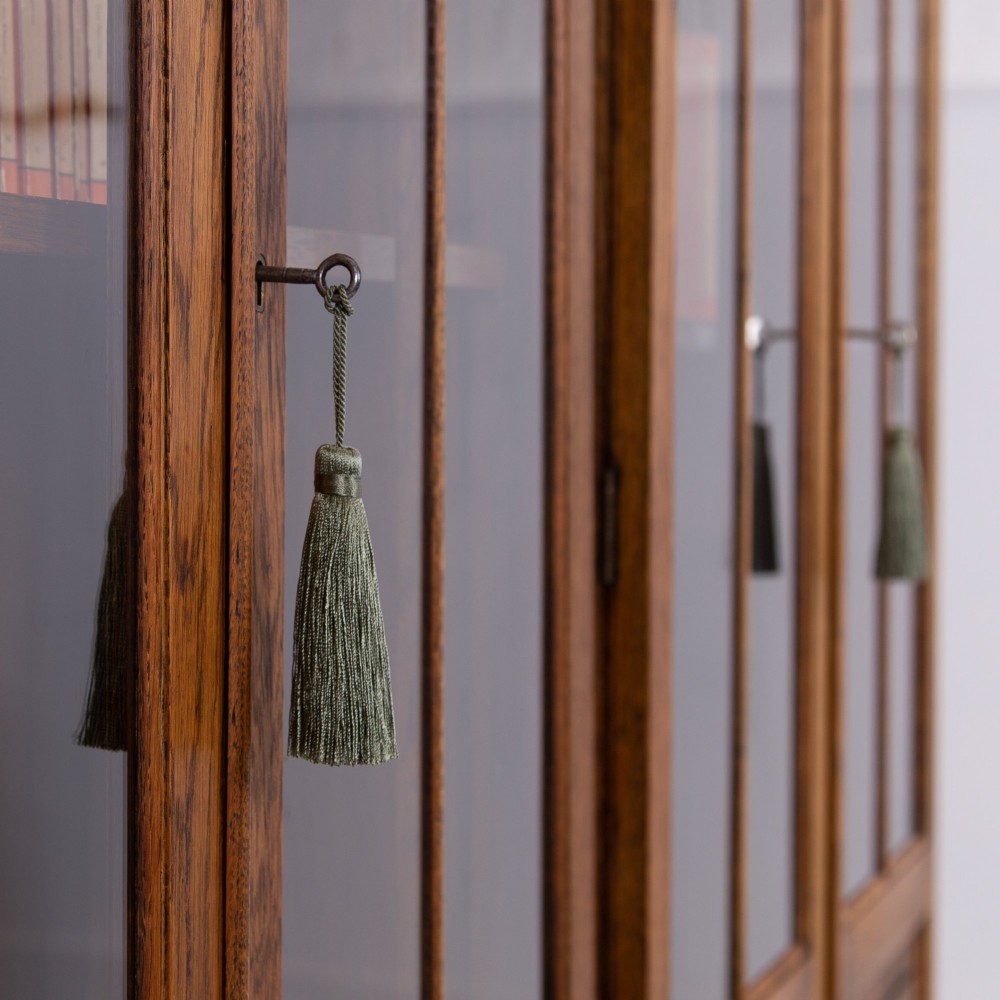 A matching pair of 1930s solid English oak bookcases featuring glazed twin doors above oval-carved lower door panels. View XIII