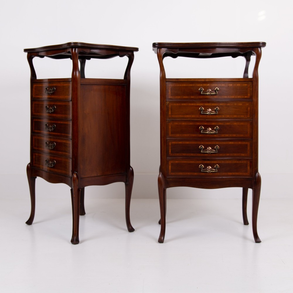 A matching pair of dark mahogany Edwardian cabinets featuring five inlaid drawers, slender cabriole legs, and an open top tray shelf.