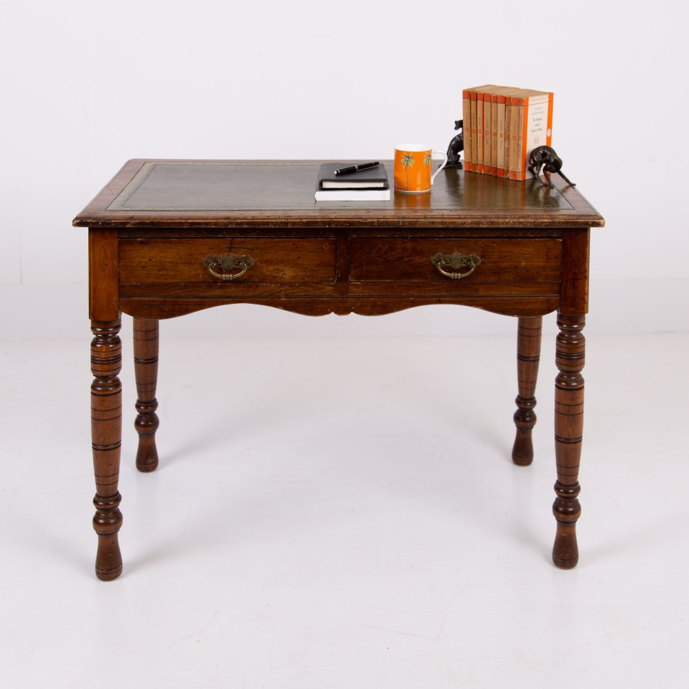A brown walnut writing desk featuring two frieze drawers with brass handles, turned legs, and a rectangular inset leather top. View III