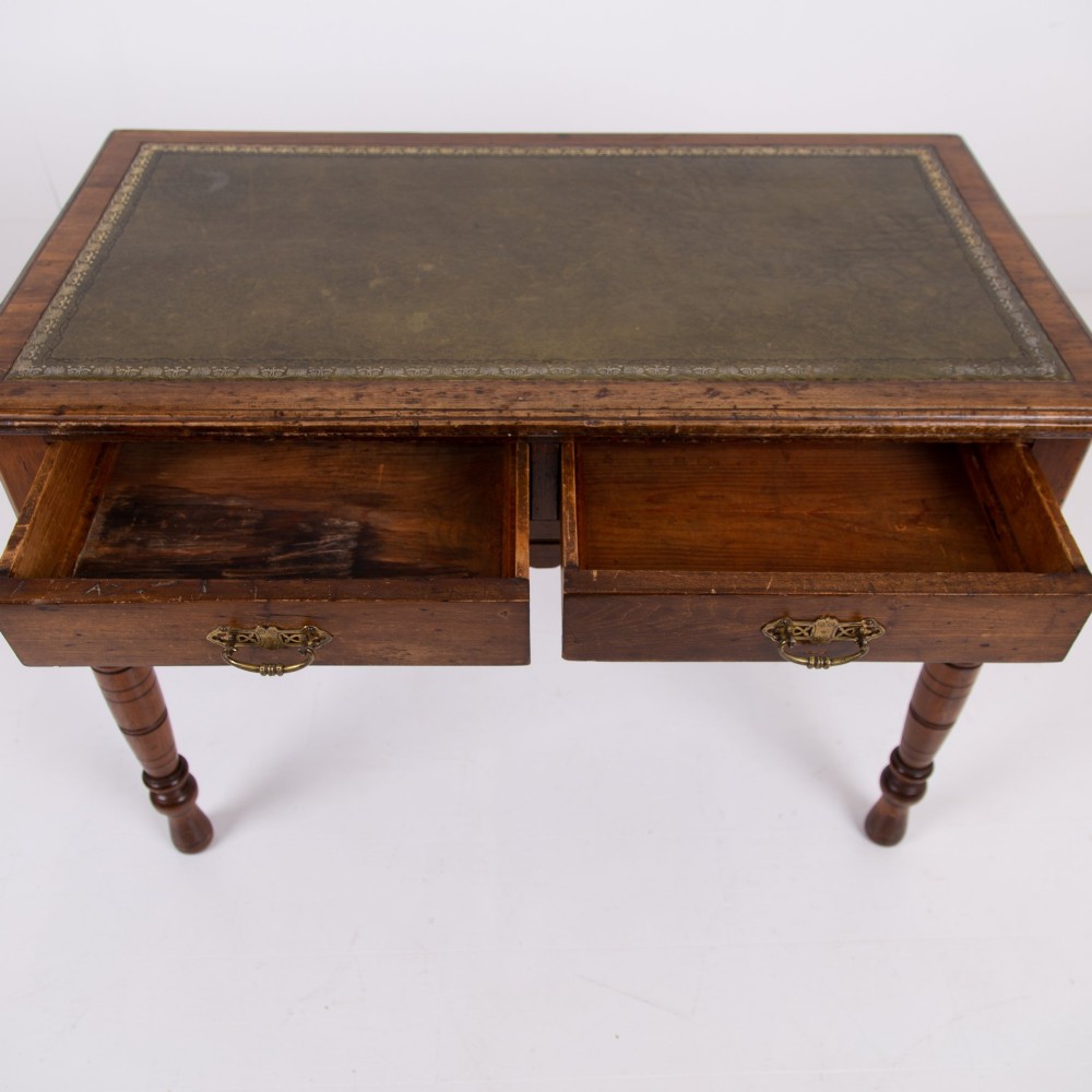 A brown walnut writing desk featuring two frieze drawers with brass handles, turned legs, and a rectangular inset leather top. View VIII