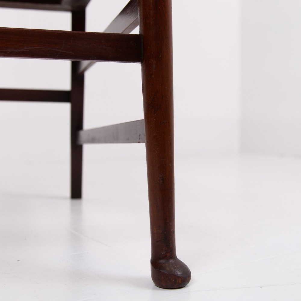 An Arts and Crafts high-backed armchair crafted from dark timber with vertical under-arm slats, architectural wings, and pale green patterned fabric upholstery. View VII