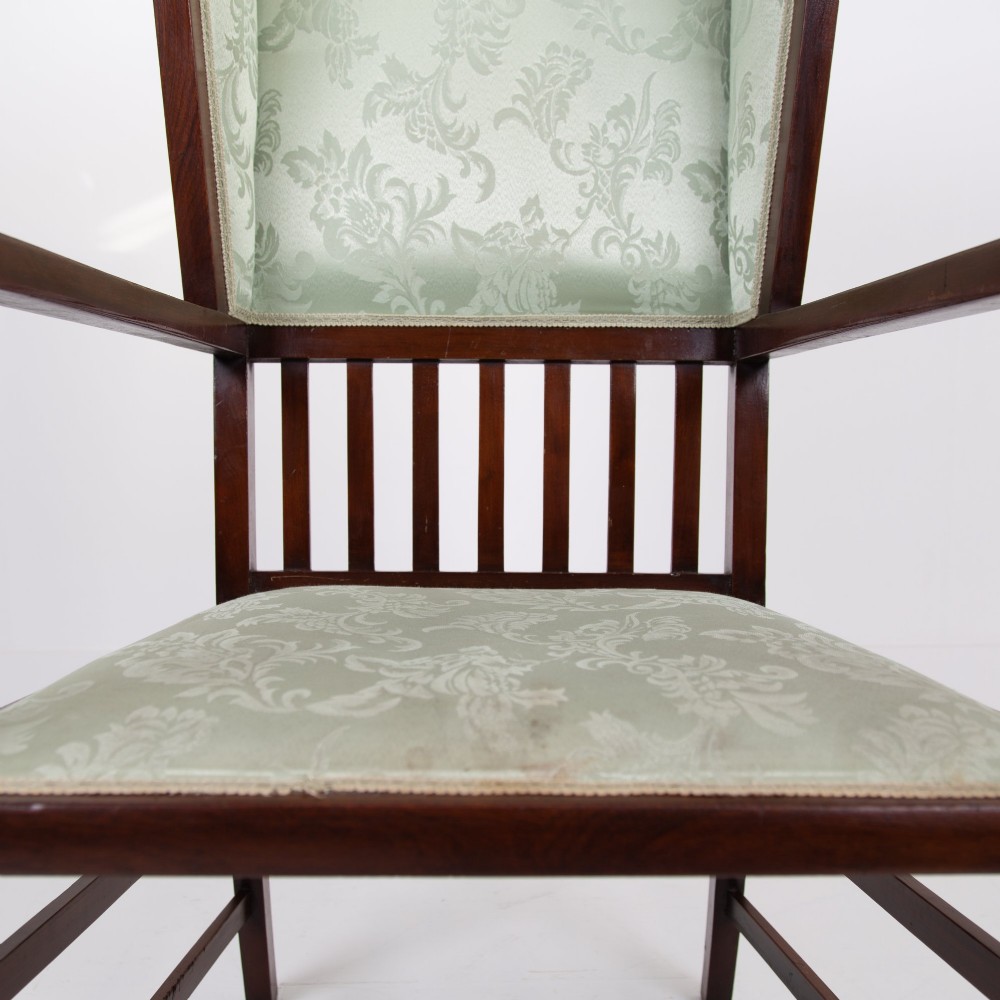 An Arts and Crafts high-backed armchair crafted from dark timber with vertical under-arm slats, architectural wings, and pale green patterned fabric upholstery. View VIII