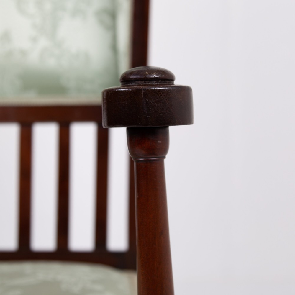 An Arts and Crafts high-backed armchair crafted from dark timber with vertical under-arm slats, architectural wings, and pale green patterned fabric upholstery. View XIII