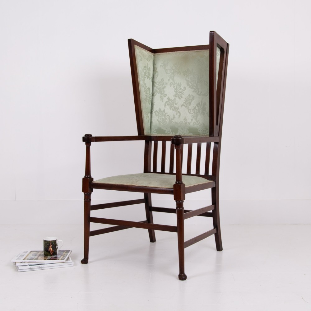 An Arts and Crafts high-backed armchair crafted from dark timber with vertical under-arm slats, architectural wings, and pale green patterned fabric upholstery. View XIV