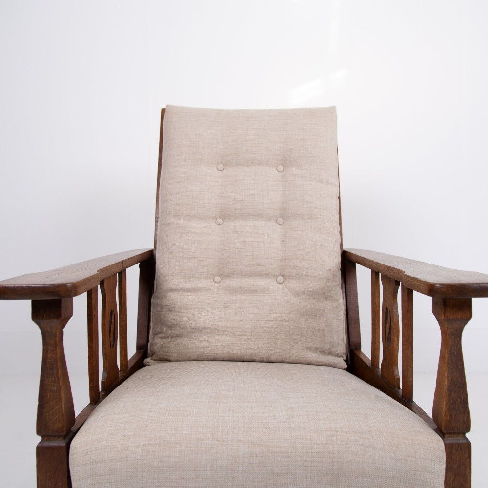 An Arts and Crafts oak reclining armchair featuring a beige buttoned cushion and pierced side splats. View V