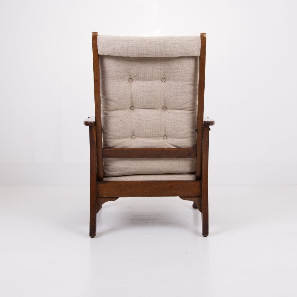 An Arts and Crafts oak reclining armchair featuring a beige buttoned cushion and pierced side splats. View VII