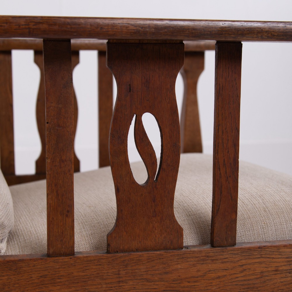 An Arts and Crafts oak reclining armchair featuring a beige buttoned cushion and pierced side splats. View IX