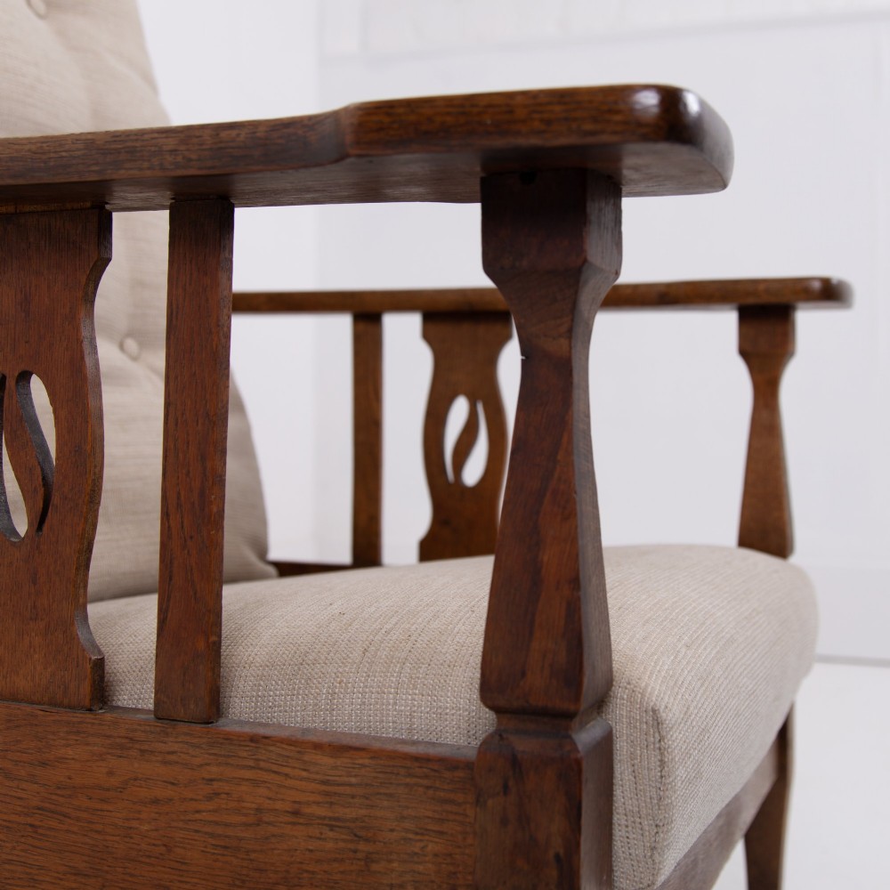 An Arts and Crafts oak reclining armchair featuring a beige buttoned cushion and pierced side splats. View XI