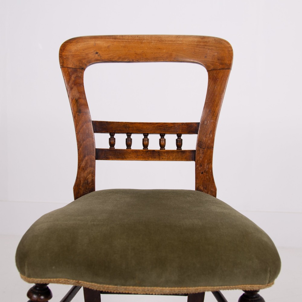 A set of six late Victorian wooden dining chairs featuring curved open backrests with spindle galleries, turned front legs, and olive green velvet seats. View IV