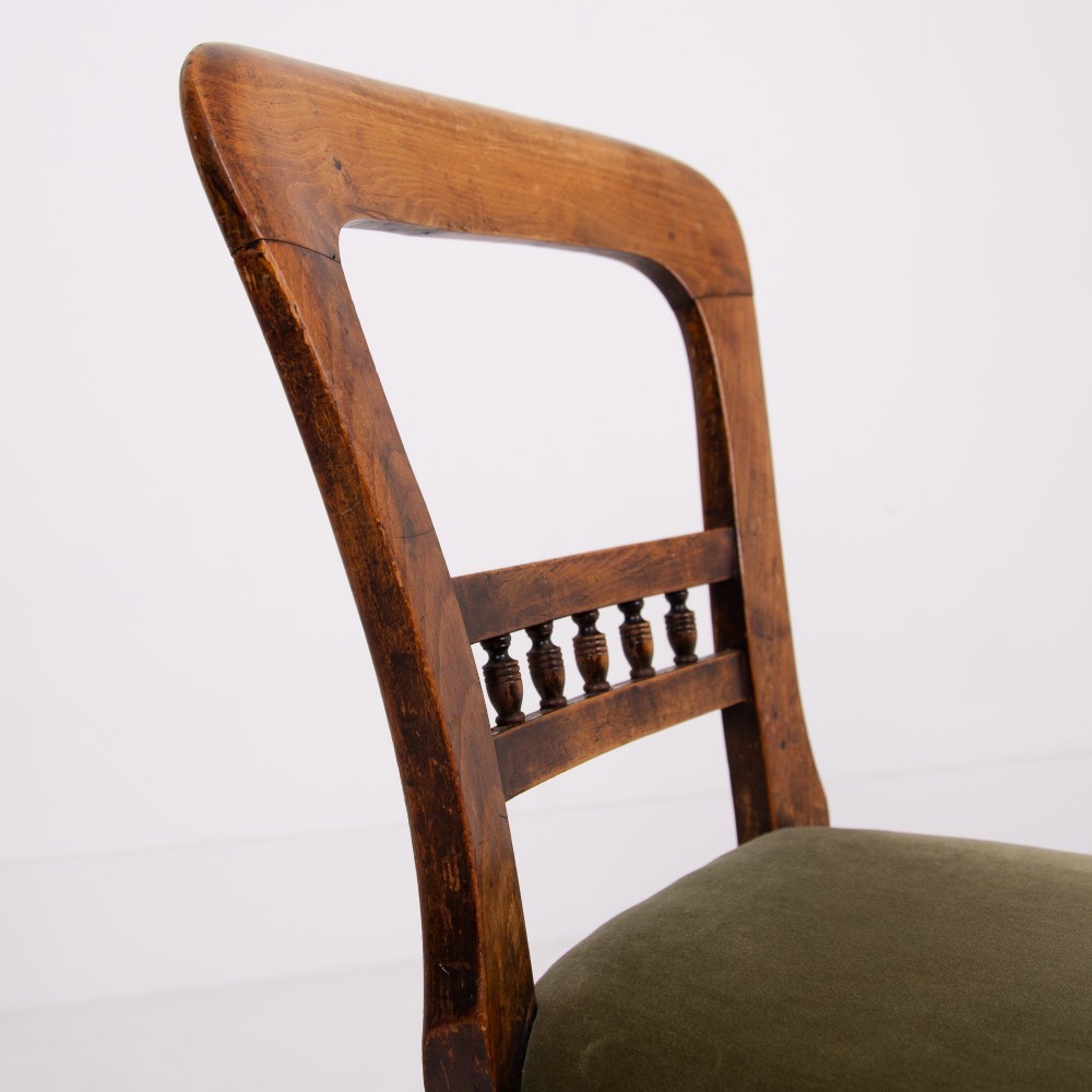 A set of six late Victorian wooden dining chairs featuring curved open backrests with spindle galleries, turned front legs, and olive green velvet seats. View V