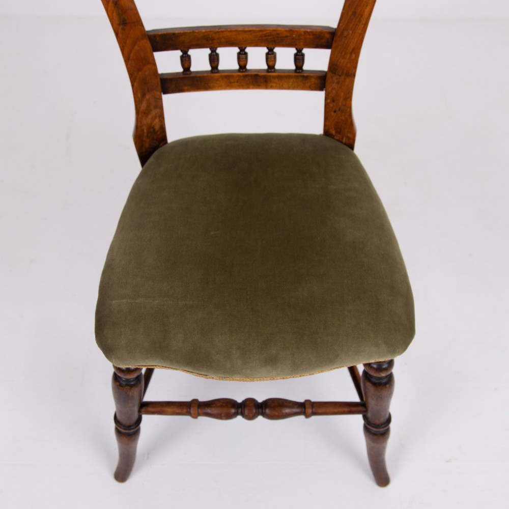 A set of six late Victorian wooden dining chairs featuring curved open backrests with spindle galleries, turned front legs, and olive green velvet seats. View X