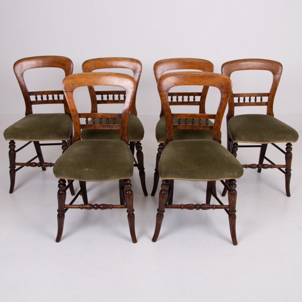 A set of six late Victorian wooden dining chairs featuring curved open backrests with spindle galleries, turned front legs, and olive green velvet seats. View XIV