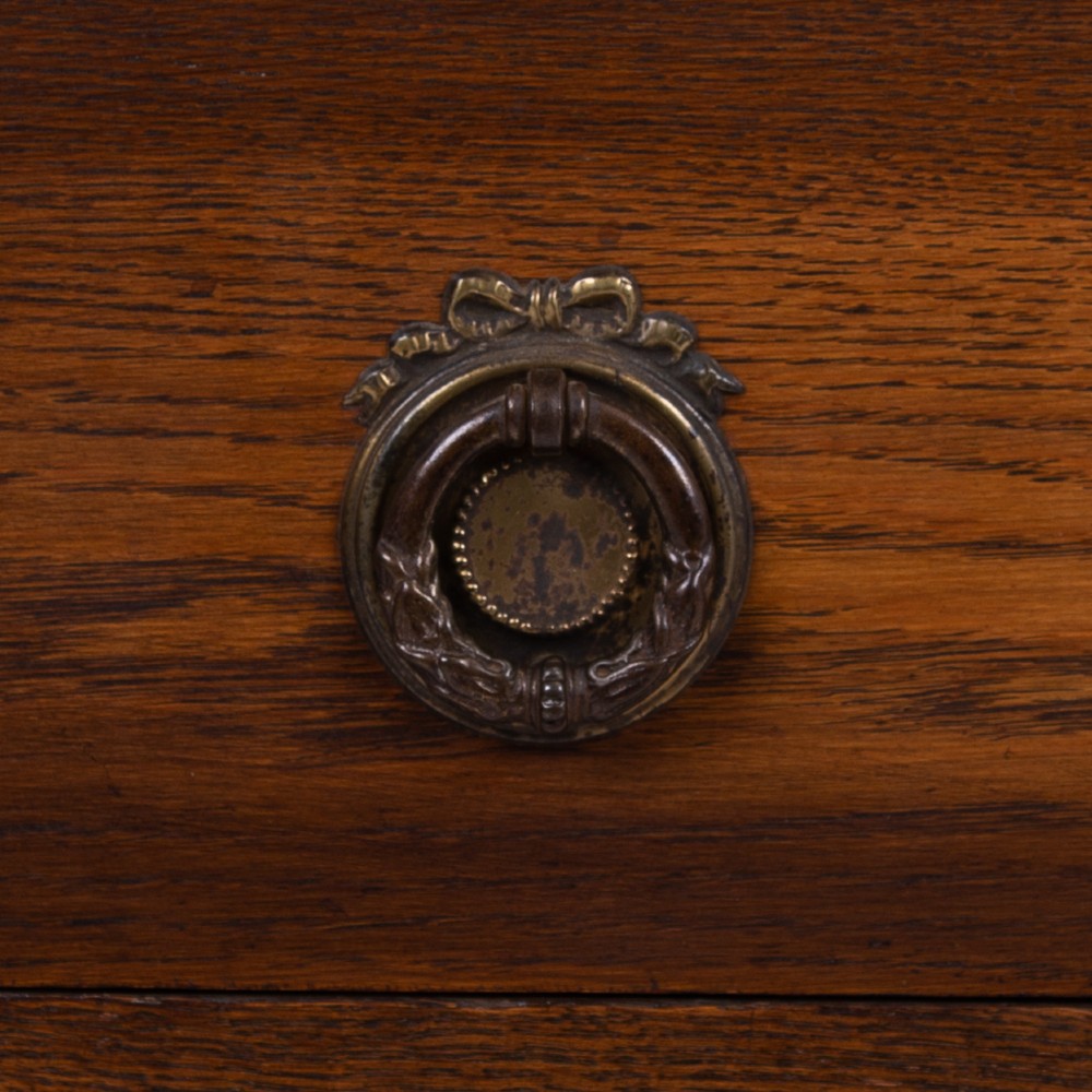 An Edwardian oak chest of drawers with two short over two long drawers, brass drop handles, a low backstand, and barley twist legs set on castors. View III