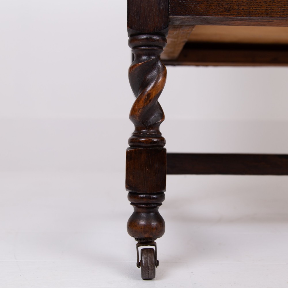 An Edwardian oak chest of drawers with two short over two long drawers, brass drop handles, a low backstand, and barley twist legs set on castors. View VII