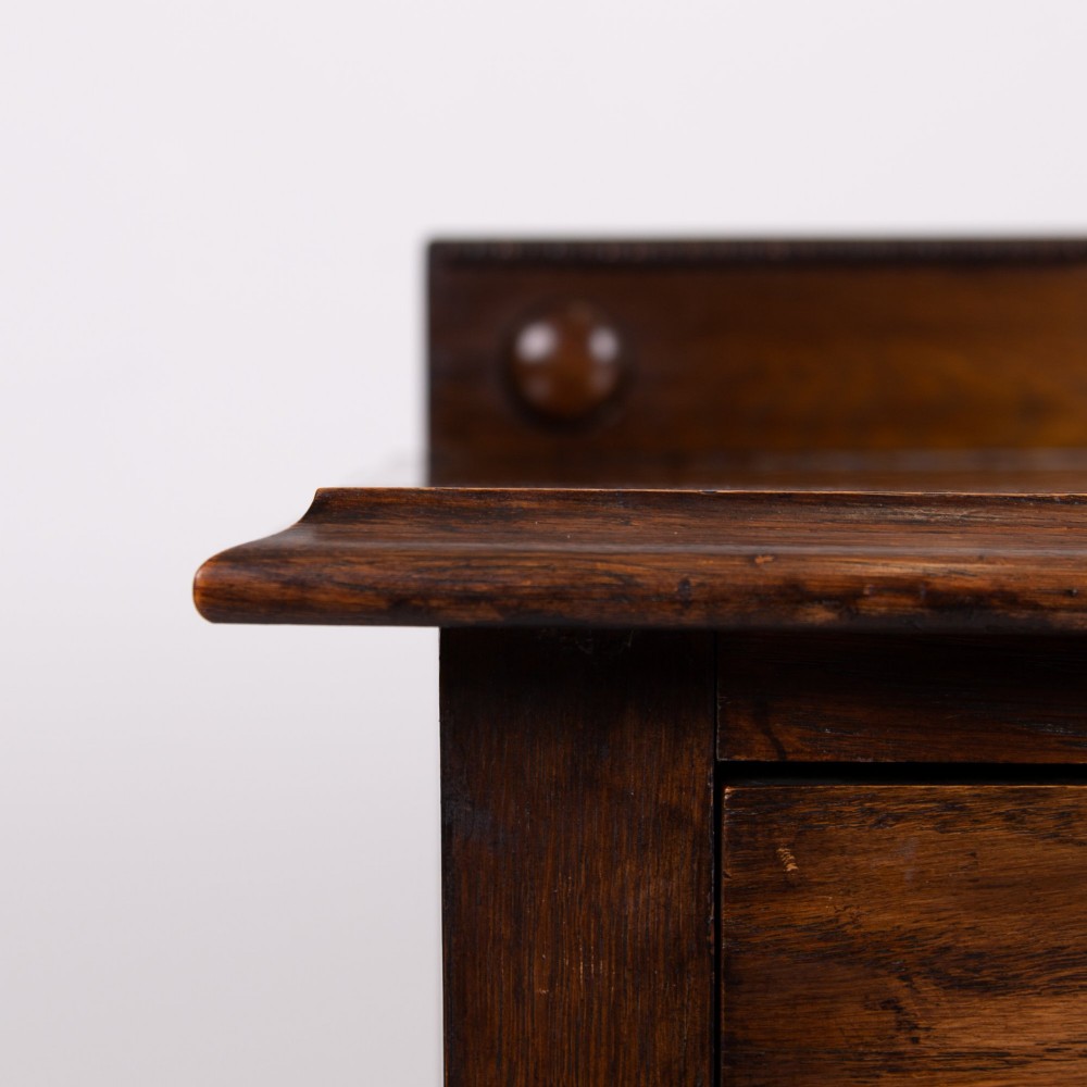 An Edwardian oak chest of drawers with two short over two long drawers, brass drop handles, a low backstand, and barley twist legs set on castors. View VIII