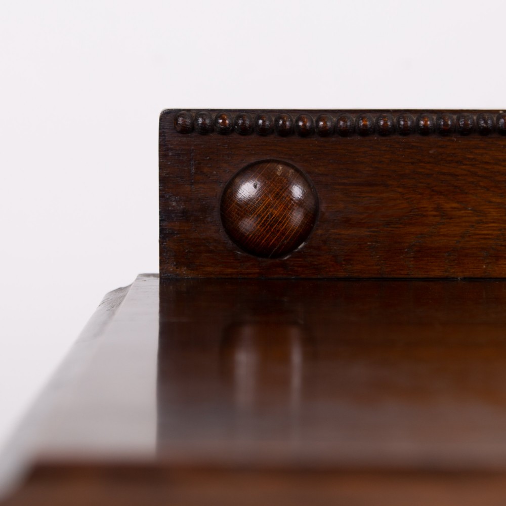 An Edwardian oak chest of drawers with two short over two long drawers, brass drop handles, a low backstand, and barley twist legs set on castors. View X