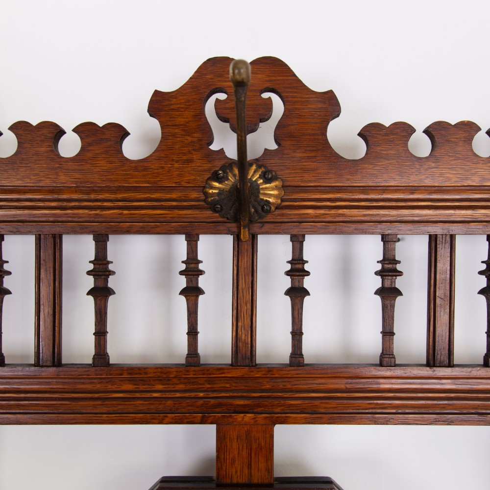 A tall Victorian golden oak hallstand featuring an octagonal central mirror, decorative ceramic tiles, brass coat hooks, a single central drawer, and lower umbrella drip trays. View X