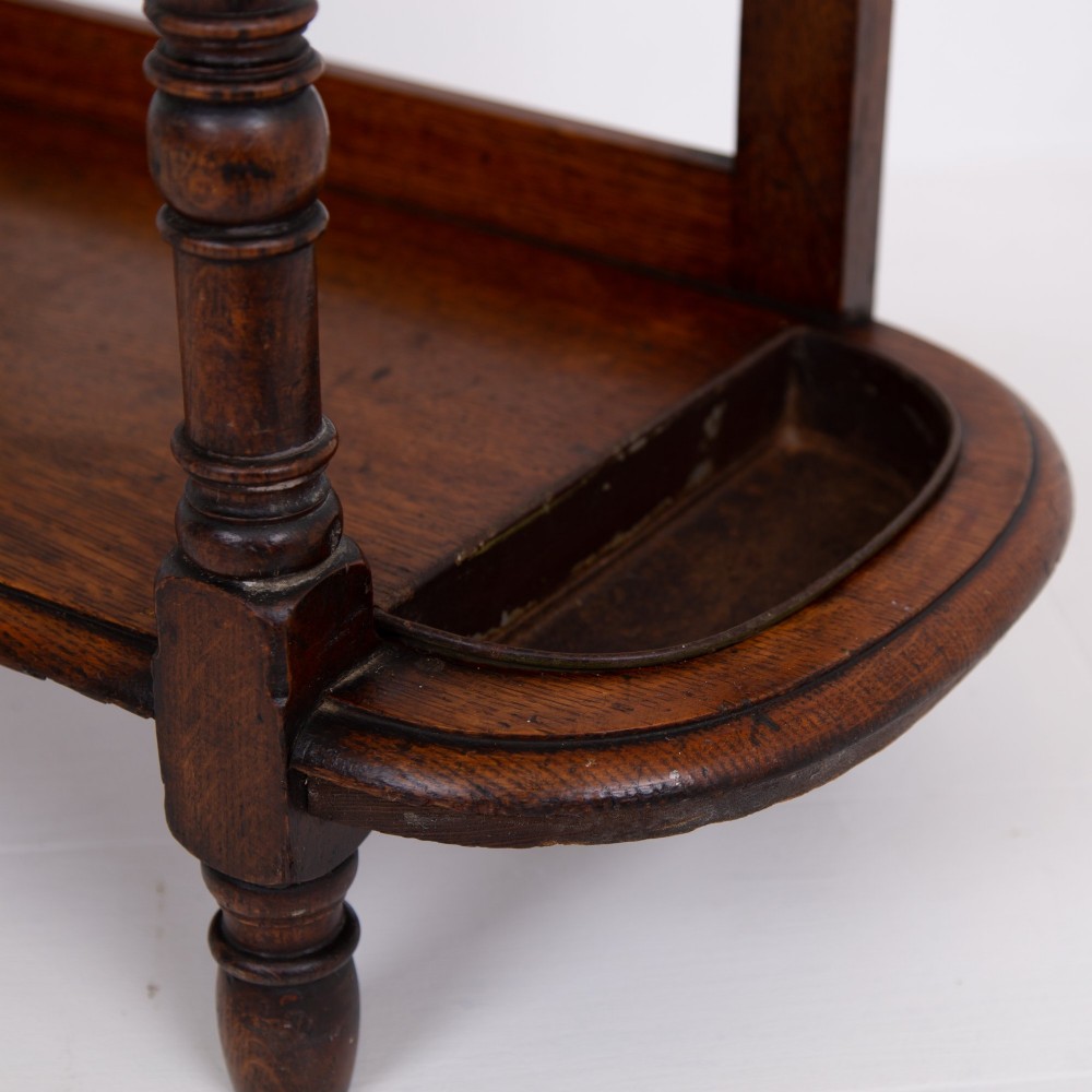 A tall Victorian golden oak hallstand featuring an octagonal central mirror, decorative ceramic tiles, brass coat hooks, a single central drawer, and lower umbrella drip trays. View XI